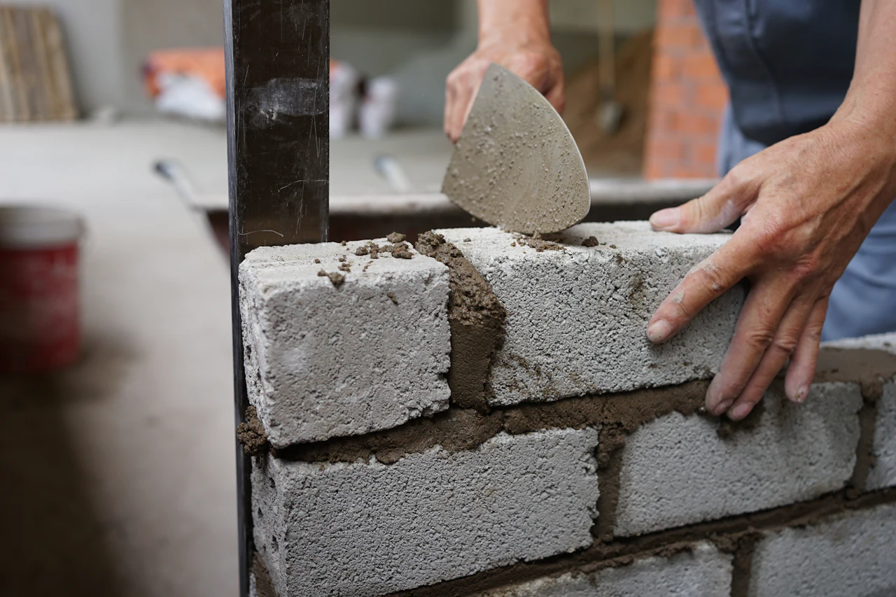 Metselaar legt een blok in een muur van snelbouwstenen