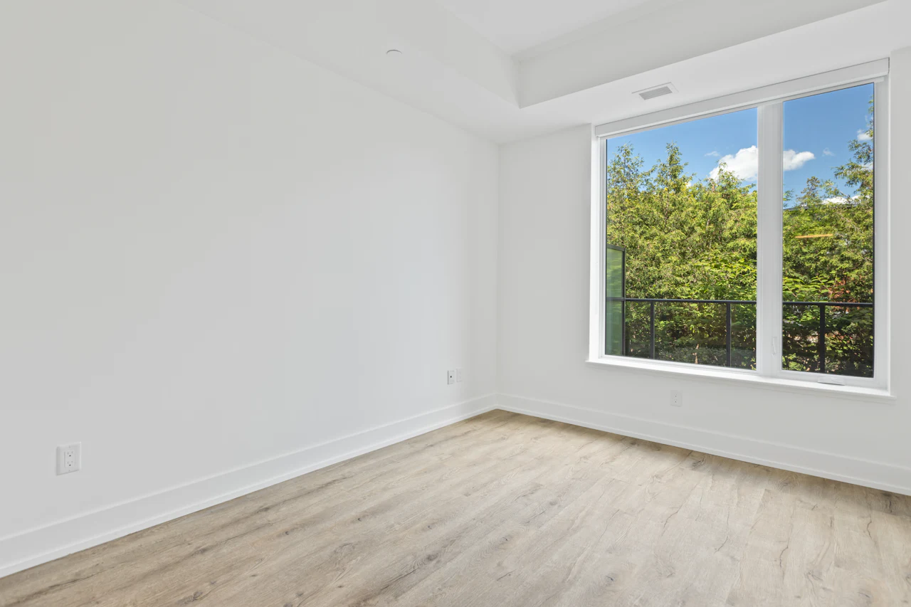 Wit afgewerkte kamer met een groot raam op de tuin